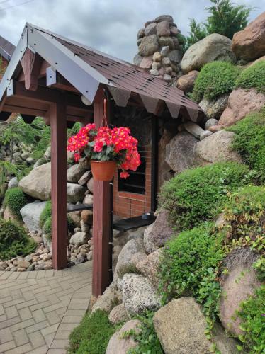 a small building with a pot of red flowers on it at Poilsio namelis Plateliai in Plateliai