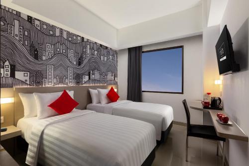 2 Betten in einem Hotelzimmer mit roten Kissen in der Unterkunft Hotel Neo Gading Solo in Solo