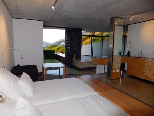 a bedroom with a large white bed and a bathroom at Snooze in Hout Bay Self-Catering in Hout Bay