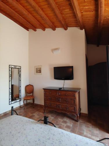 a bedroom with a bed and a tv and a chair at Tenuta Bellaprima CALTAGIRONE in Niscemi