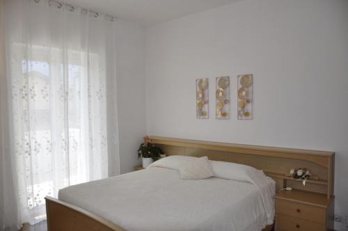 ein Schlafzimmer mit einem weißen Bett und einem Fenster in der Unterkunft Appartamento Alba in Riva del Garda