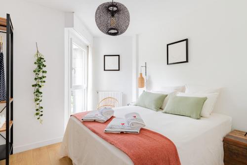 een witte slaapkamer met een bed met handdoeken erop bij L'Artistik - Appartement 5 min à pied du port et parking privé in Vannes