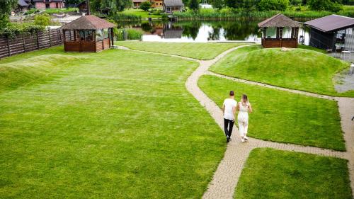 Un uomo e una donna che camminano lungo un sentiero in un parco di Eden Resort a Yasnogorodka