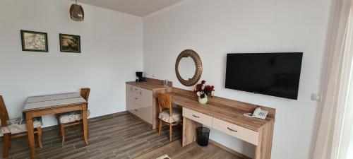 a living room with a television and a desk with a table at Aparthotel Olympus Plaza - SPA & Indoor Pool in Kranevo