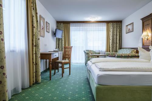 a hotel room with two beds and a desk at Almhof Lackner in Ried im Zillertal
