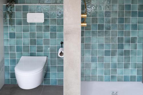 a blue tiled bathroom with a toilet and a tub at Het Heerenlogement Beusichem in Beusichem