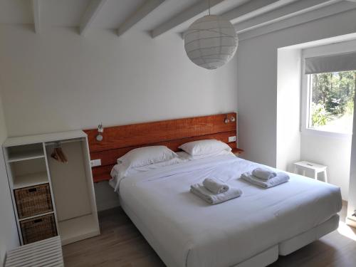 1 dormitorio con 1 cama blanca grande y toallas. en Luz da Lúa - Casa del campo, en Muxía