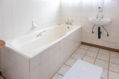 a white bath tub and a sink in a bathroom at Dullstroom Inn in Dullstroom