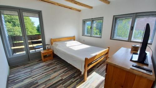 a bedroom with a bed and a desk and windows at Panna Cottage in Badacsonytomaj