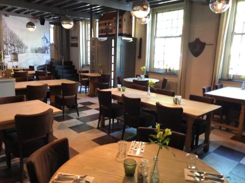 a restaurant with wooden tables and chairs and windows at Het Heerenlogement Beusichem in Beusichem