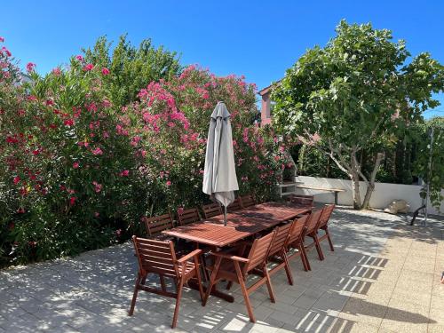 a table and chairs with an umbrella and flowers at Vila Maria Nin in Nin