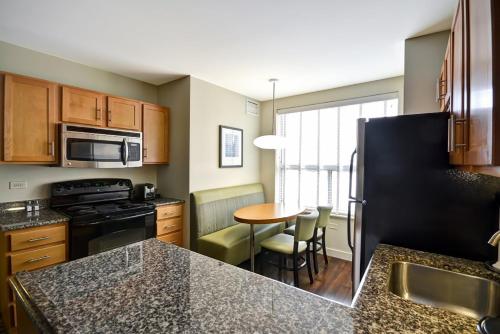 a kitchen with a black refrigerator and a table at Hyatt House Naperville/Warrenville in Warrenville