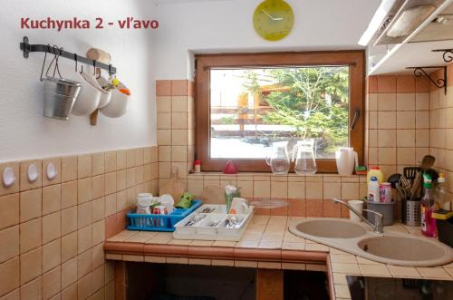 a tiled kitchen with a sink and a window at Aqualand chata - Športové a výcvikové stredisko ZPS in Dedinky