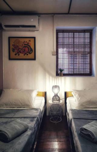 a room with two beds and a window in it at Treehouse Hostel in Kuching