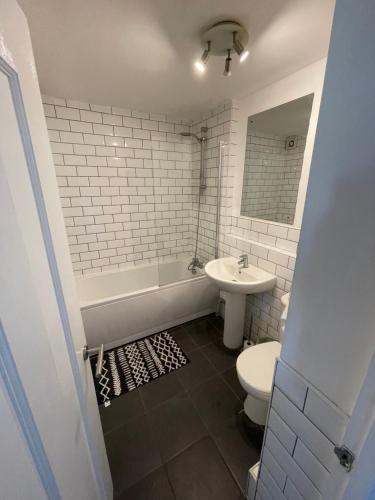 a bathroom with a tub and a toilet and a sink at Monochrome 16 , Brentwood in Brentwood