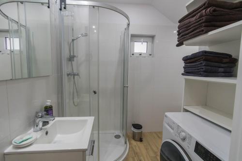 a white bathroom with a shower and a sink at Nad Dadajem Domki do Wynajęcia in Biskupiec
