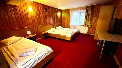 ブシュテニにあるPensiunea Kalinderの赤いカーペットフロアの客室で、ベッド2台が備わります。