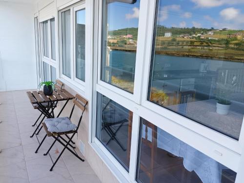 a balcony with windows and a table and chairs at Apartamento Ría Navia in Navia