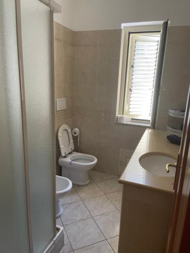 a bathroom with a toilet and a sink and a window at Confortevole e Luminoso Appartamento 100mq a Falerna con Vista sul Paese e sul Promontorio con Free WiFi Free Parking e Smart TV in Falerna