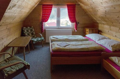 a attic room with two beds and a window at Aqualand chata - Športové a výcvikové stredisko ZPS in Dedinky