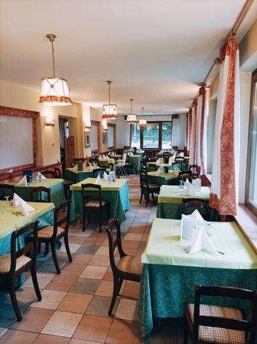 a dining room with green tables and chairs at IHR Hotel Villa Emma in Canazei