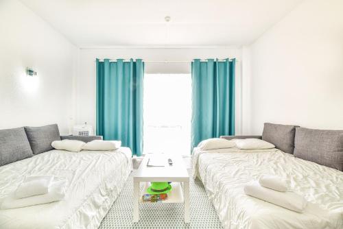two beds in a room with blue curtains at SouthView Studio Silchoro AL in Albufeira