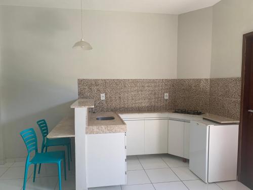 una cucina con armadi bianchi e sedie blu di Pousada Vovó Haidê a Angicos