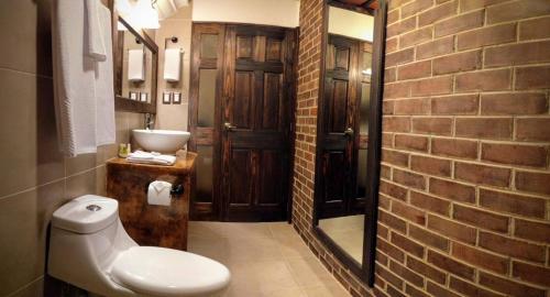 a bathroom with a toilet and a sink and a brick wall at Hotel Posada de la Luna in Antigua Guatemala