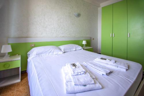 a bedroom with a white bed with towels and green cabinets at Hotel San Pietro Chiavari in Chiavari