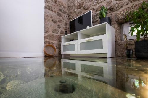 a living room with a tv and a glass floor at Mill House by the River in Arcos de Valdevez