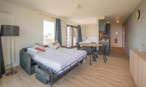een slaapkamer met een bed en een tafel en een keuken bij Angel by the Waves in Oostende