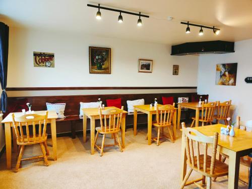 una sala da pranzo con tavoli e sedie in legno di Waterfront Rest B&B a Clifden