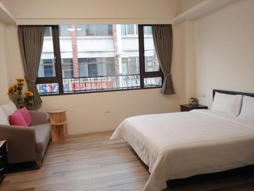 a bedroom with a bed and a couch and windows at JINGTONGYULI BnB 民宿編號2415 in Yuli