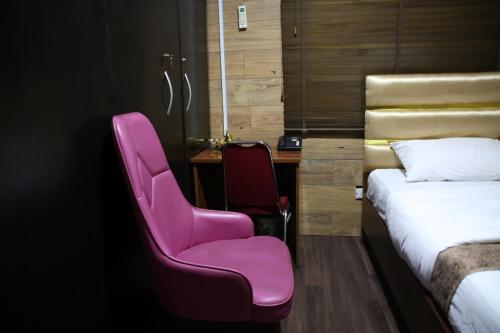 Zimmer mit einem rosa Stuhl und einem Schreibtisch in der Unterkunft HPLagos in Lagos