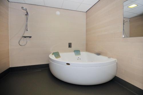a white tub in a bathroom with a shower at Camping de Duinhoeve Chalet Zeeland not for companies in Burgh Haamstede