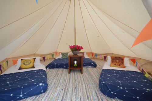 a tent with two beds and a table with flowers at Starlight Glamping 