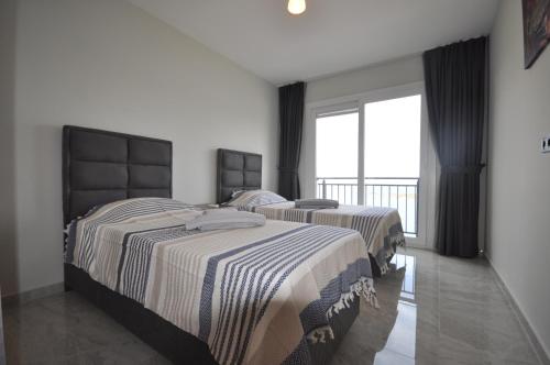 two beds in a room with a large window at Castamar Residence in Bodrum City