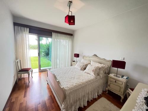 een witte slaapkamer met een bed en een groot raam bij Vila Chã Beach House by Trip2Portugal in Vila Chã