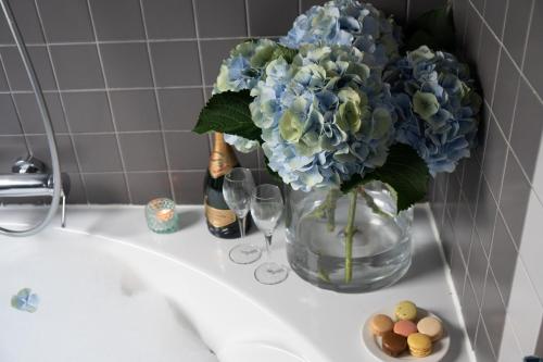 a vase with blue flowers and wine glasses on a sink at Hotel Mademoiselle in Paris