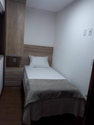 uma cama num quarto com uma parede branca em Hotel Wilson em Teixeiras