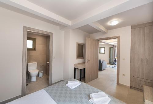 a white bedroom with a bed and a bathroom at Villelia View Villas 2 in Apolpaina