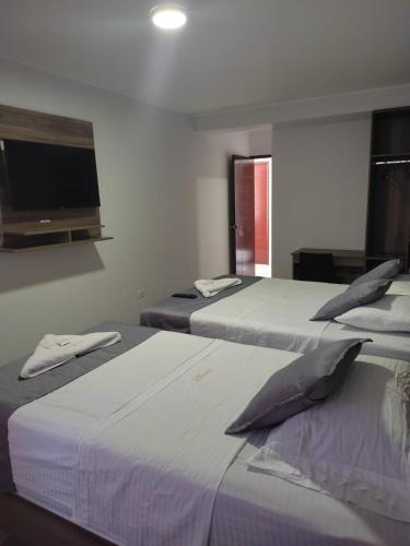 a room with three beds and a flat screen tv at Hotel Terrazas Del Mar in Huacho