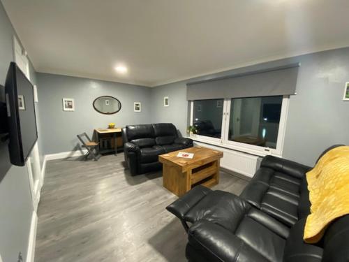 a living room with black leather furniture and a window at Burnt Island 2 bed apartment with stunning views in Fife