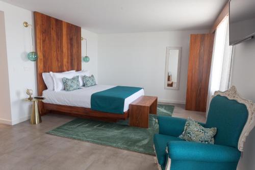 a bedroom with a bed and a blue chair at Casa dos Romeiros in Santa Bárbara