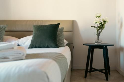 una cama con un jarrón de flores sobre una mesa en Residence Antico Torchio, en Dervio