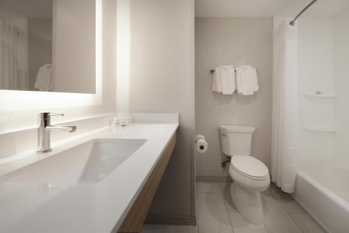 Holiday Inn Express & Suites - Williamstown - Glassboro, an IHG Hotel في ويليامزتاون: حمام أبيض مع حوض ومرحاض