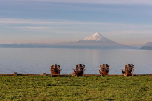 four chairs sitting in front of a lake with a mountain at Casa Molino Hotel Boutique & Restaurant in Puerto Varas