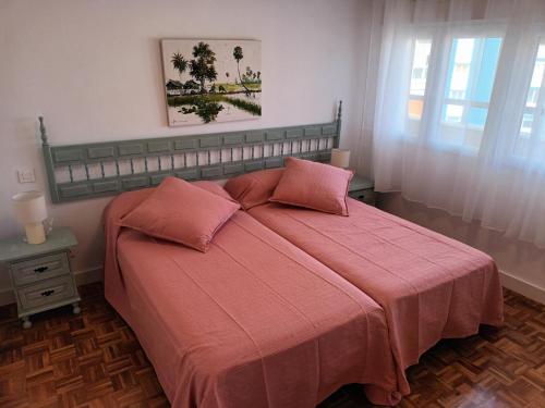 a bedroom with a large bed with pink sheets at NEW MARITIMO in Málaga