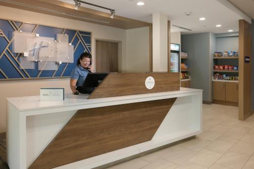a woman sitting at a counter in a pharmacy at Holiday Inn Express & Suites - Williamstown - Glassboro by IHG in Williamstown