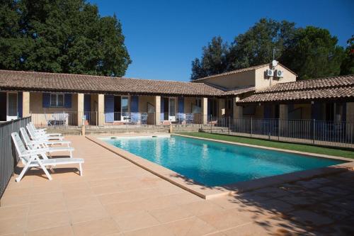 a swimming pool with white chairs next to a house at Appartements " Le Clos De La Cerisaie" in Castillon-du-Gard